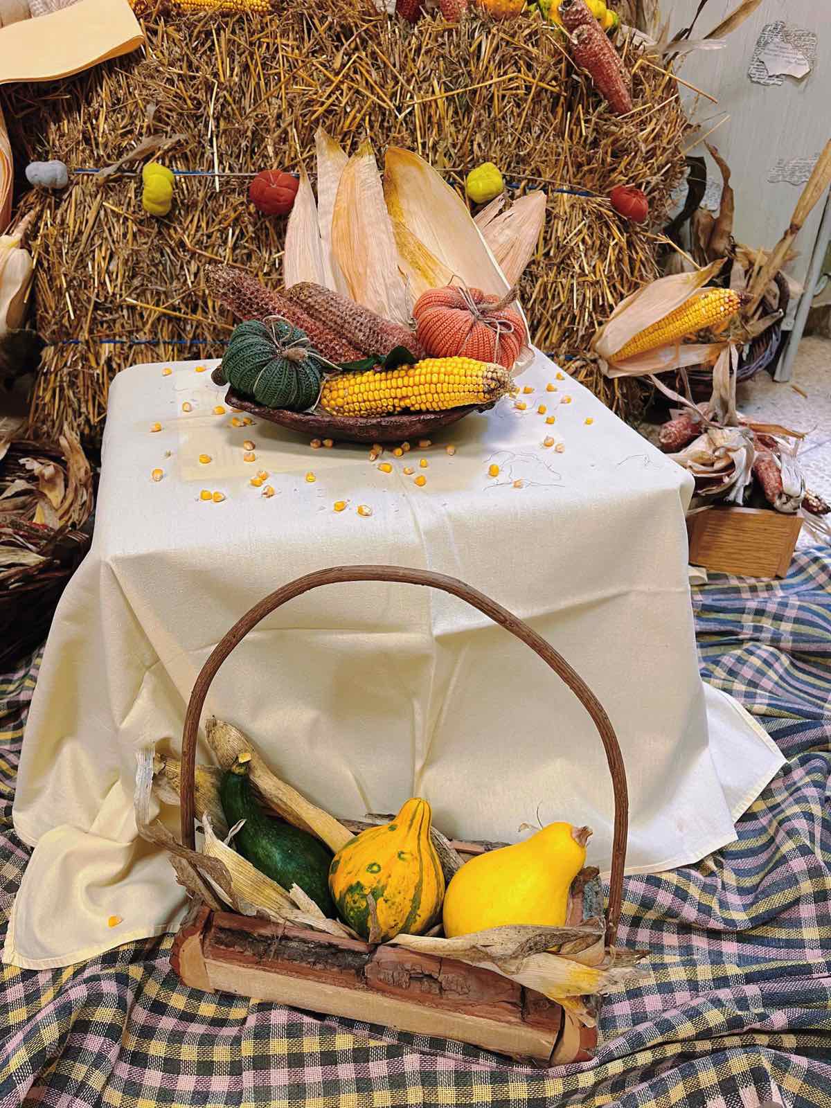 A basket of corn and squash on a table

Description automatically generated