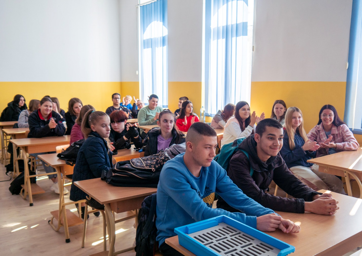 A group of people sitting at desks in a classroom

Description automatically generated