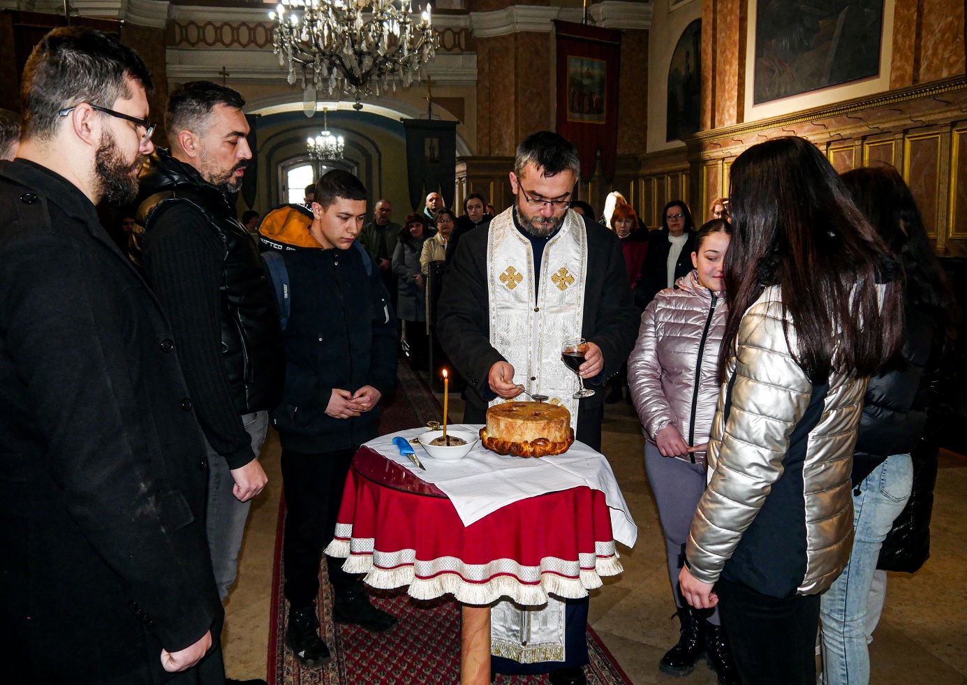 A group of people around a table with a cake

Description automatically generated