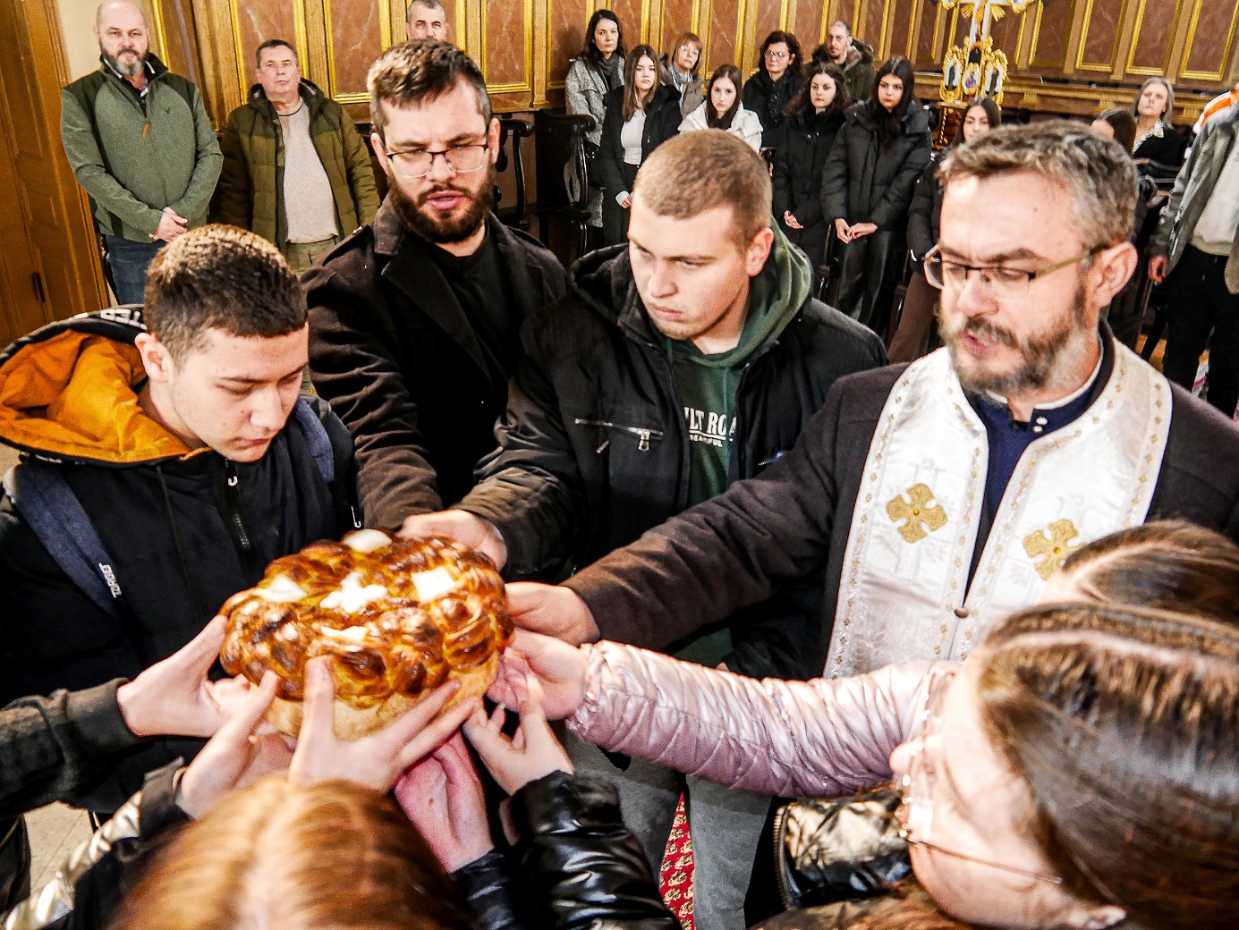 A group of people holding a loaf of bread

Description automatically generated