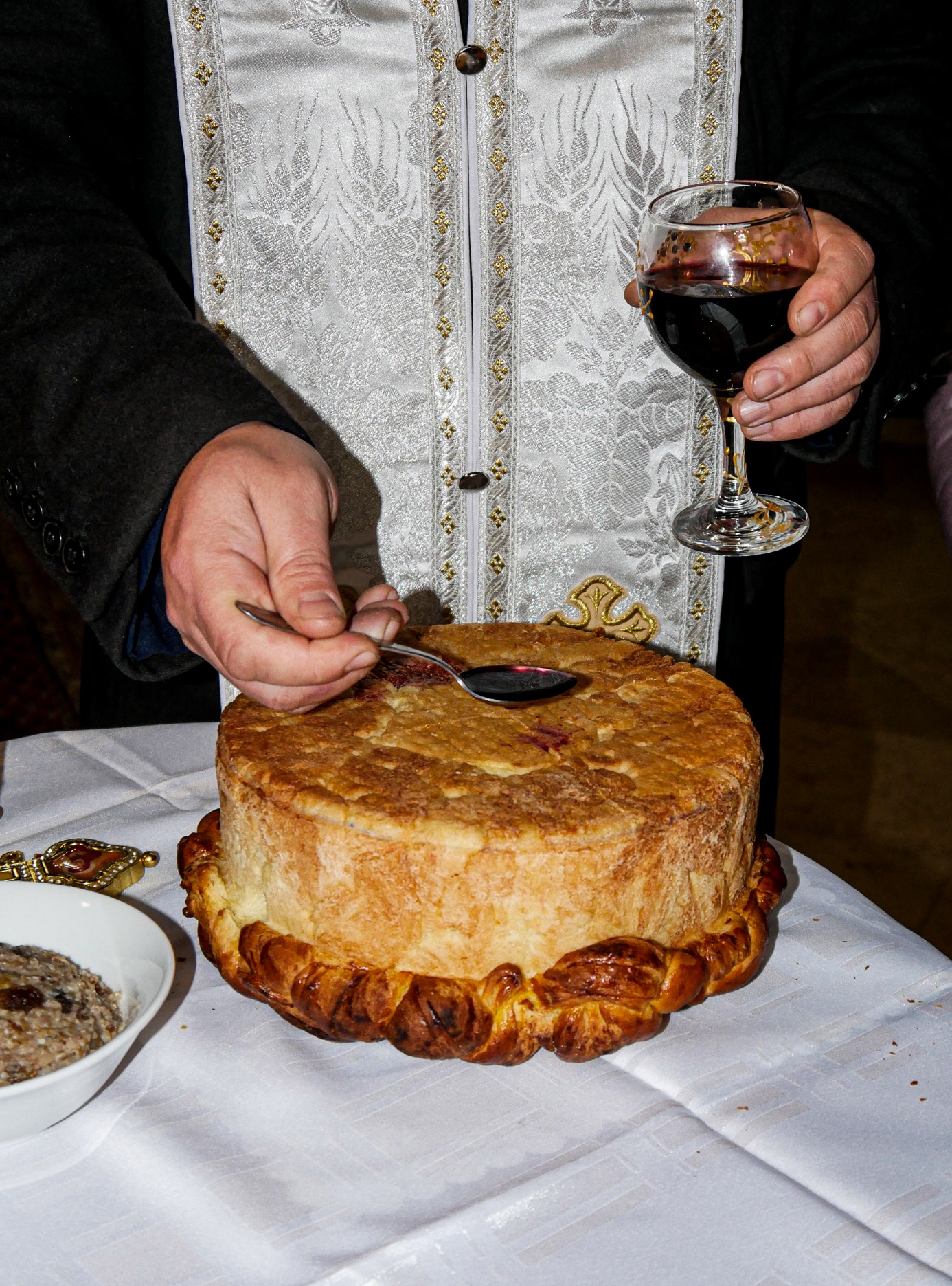 A person holding a glass of wine and a cake

Description automatically generated